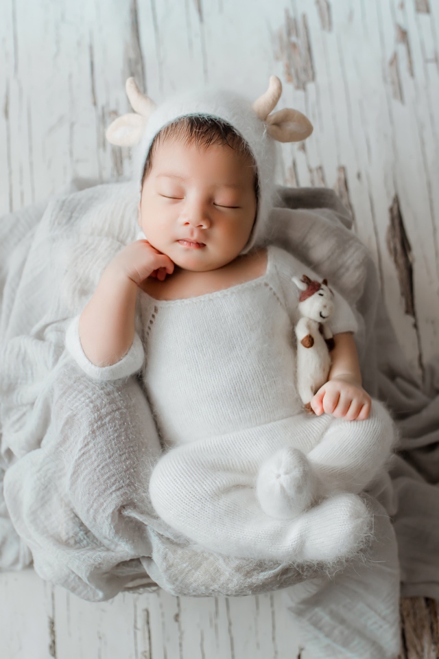 Маленький спящий грудной ребенок в белом костюме