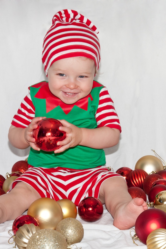 Маленький улыбающийся мальчик с елочными украшениями