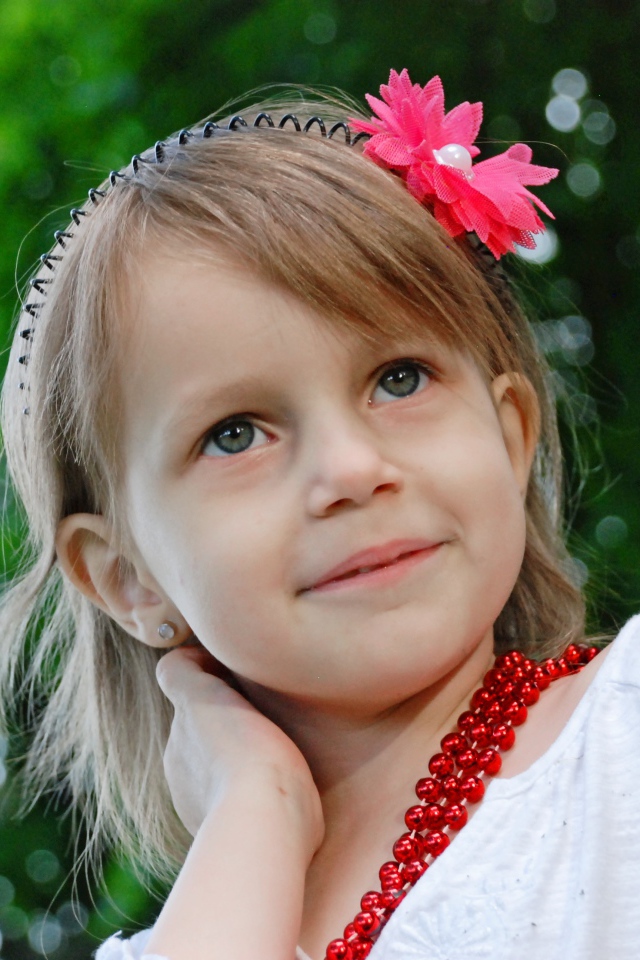 Маленькая улыбающаяся девочка у дерева 