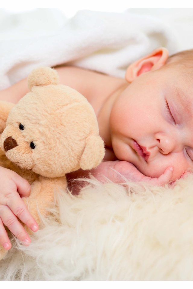Новорожденный ребенок спит с игрушечным медведем