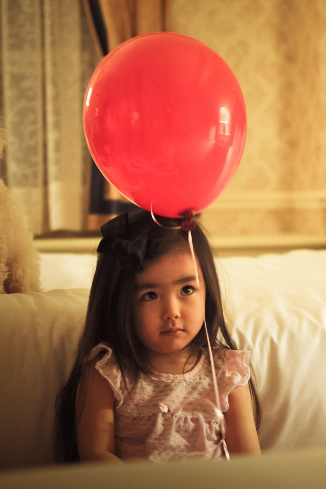 Грустная девочка азиатка с красным шариком