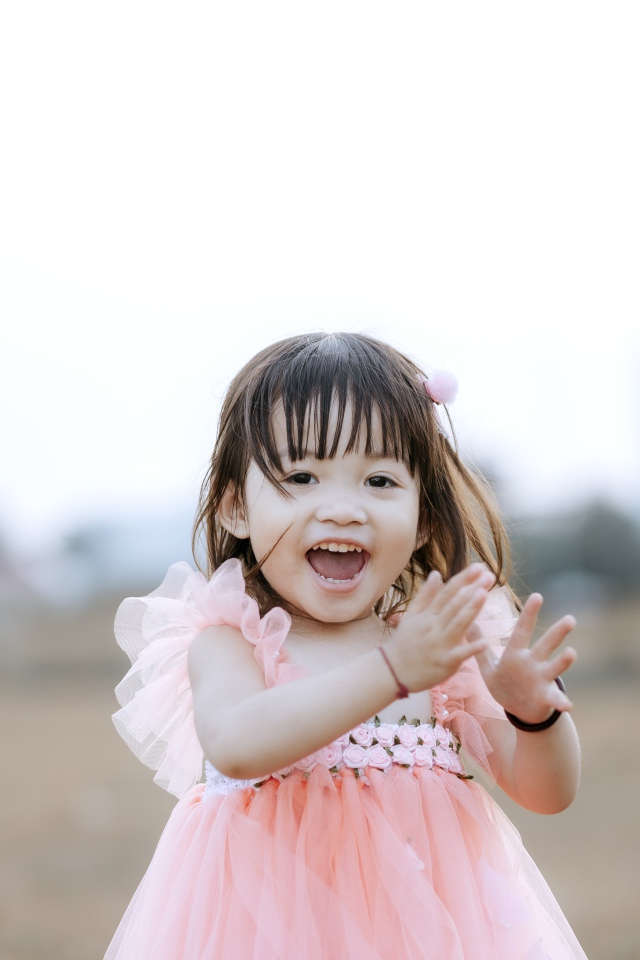 Довольная маленькая девочка в розовом платье 