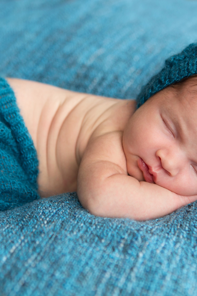 Спящий грудной ребенок лежит на голубом покрывале 