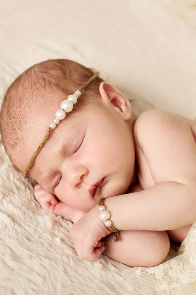 Спящий грудной ребенок с украшением с жемчугом на голове 
