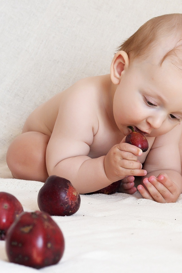 Маленький грудной ребенок грызет красные яблоки 