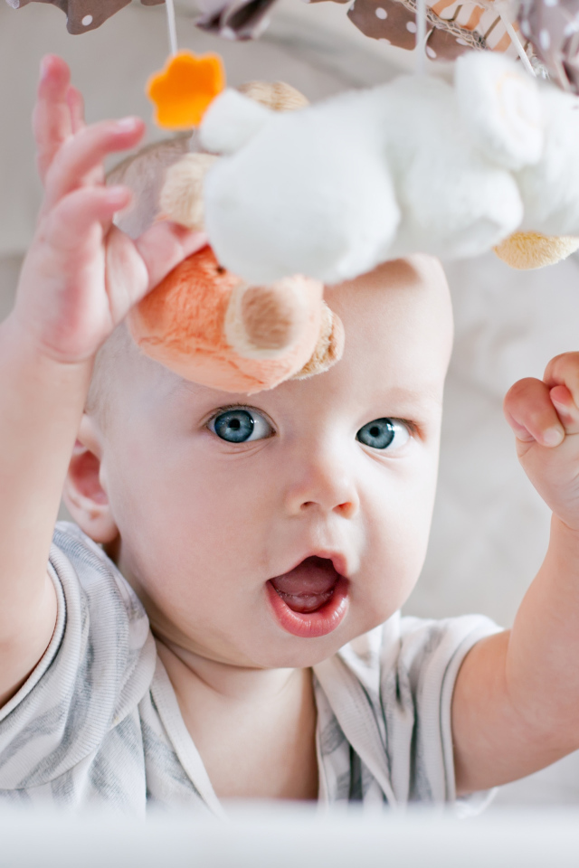Маленький грудной ребенок в коляске с игрушками 
