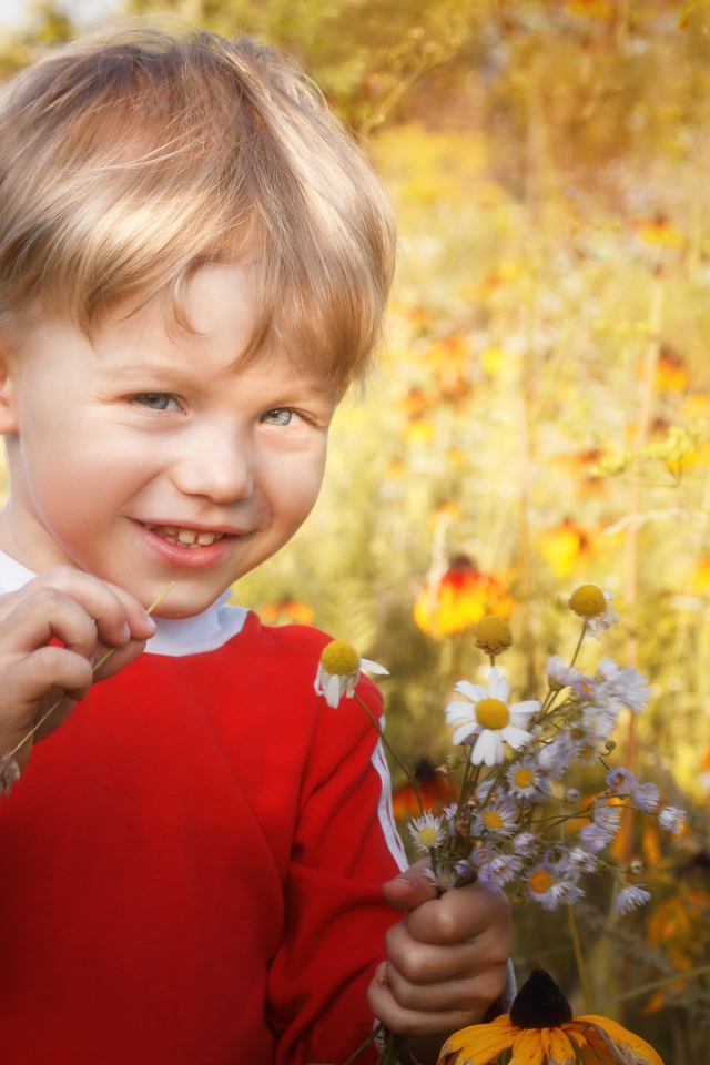 Улыбающийся голубоглазый мальчик с полевыми цветами 