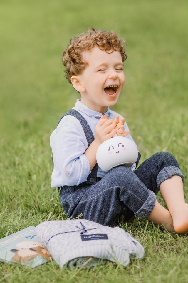 Улыбающийся мальчик сидит на траве
