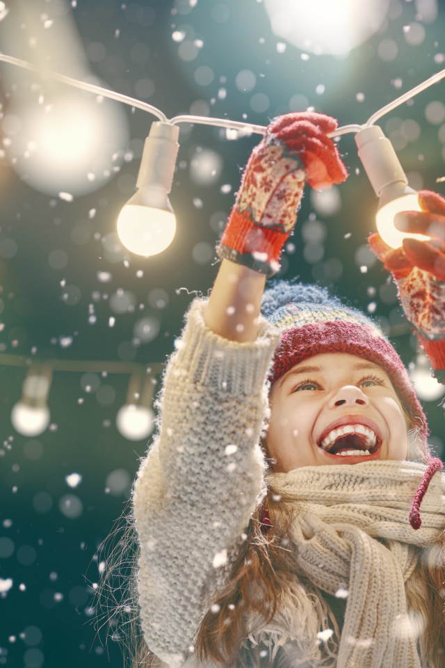 Улыбающаяся девочка вешает лампочки 