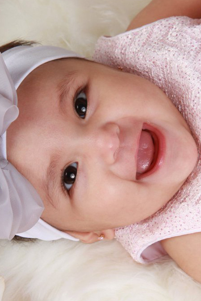 Улыбающаяся девочка в розовом платье с бантом на голове