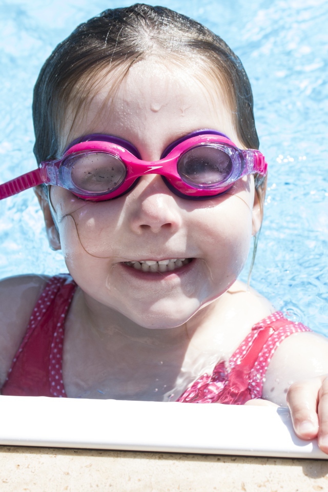 Улыбающаяся девочка в очках в бассейне