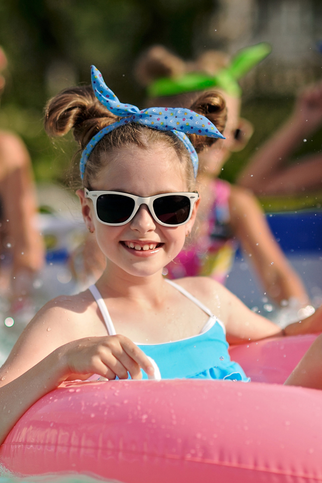 Улыбающаяся девочка со спасательным кругом в бассейне 