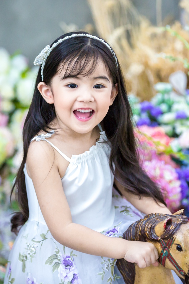 Улыбающаяся маленькая девочка азиатка на лошадке