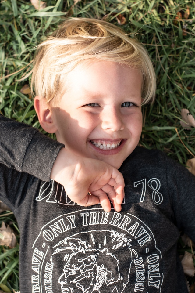 Улыбающийся маленький мальчик лежит на траве