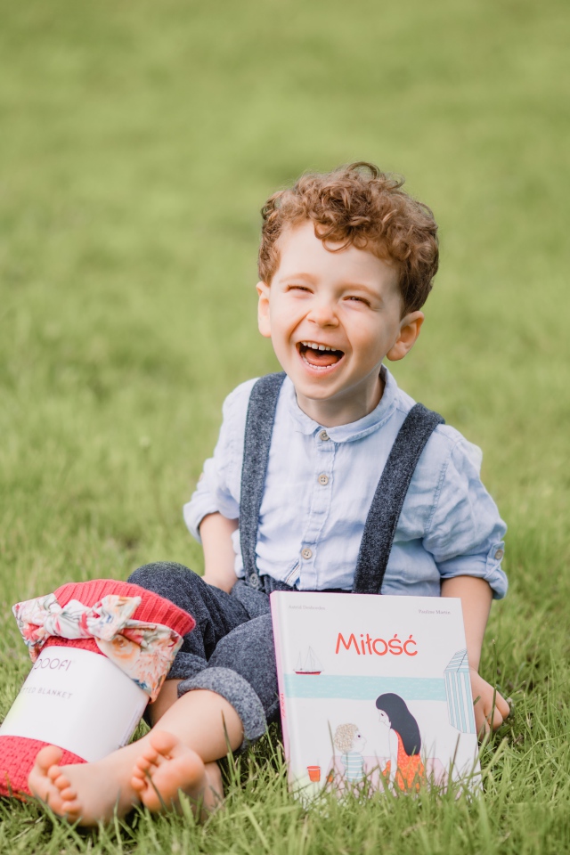 Улыбающийся маленький мальчик сидит на зеленой траве