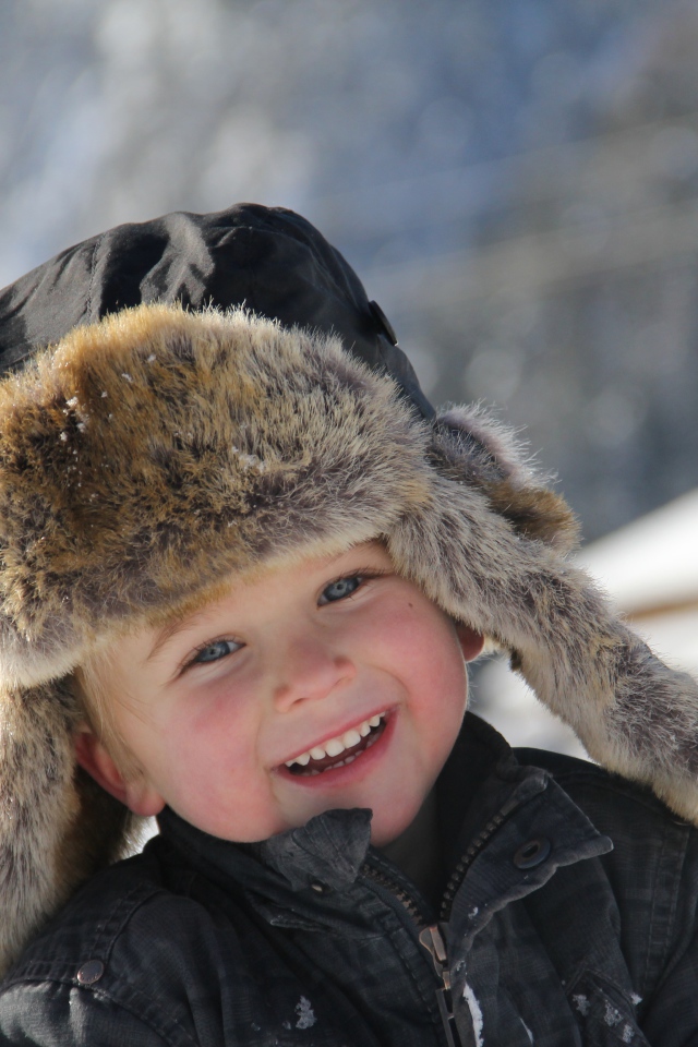 Улыбающийся  маленький мальчик в зимней шапке 