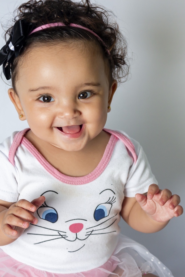 Улыбающаяся маленькая девочка на сером фоне 