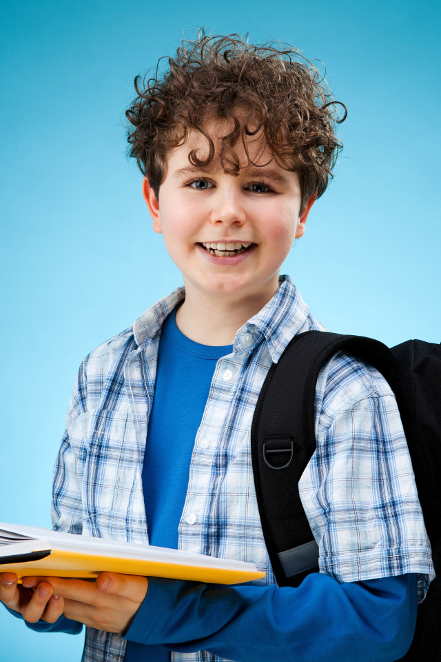 Улыбающийся мальчик школьник с книгой в руках 