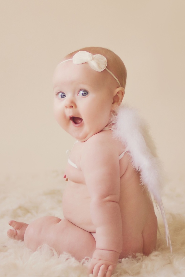 Удивленный грудной ребенок с белыми крыльями за спиной 