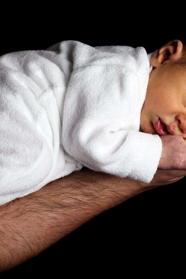 Грудной ребенок спит на руке у папы