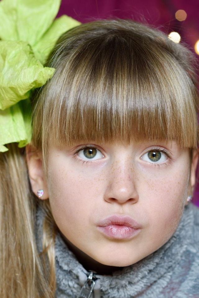 Лицо зеленоглазой девушки с бантом на голове 