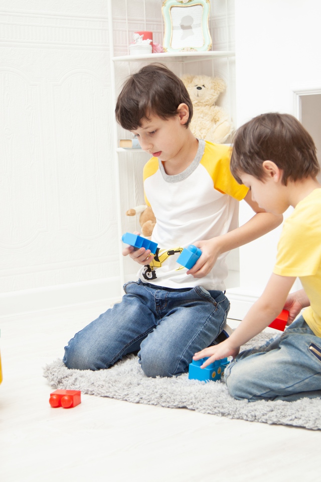 Два маленьких мальчика играет на полу