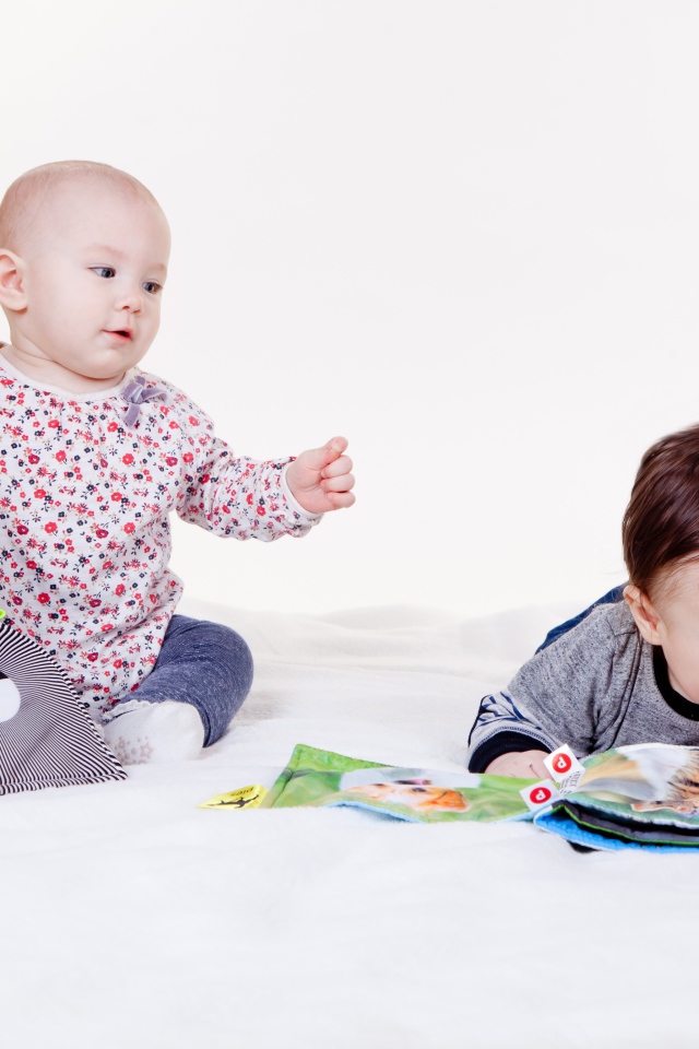 Два маленьких ребенка играют на белом фоне