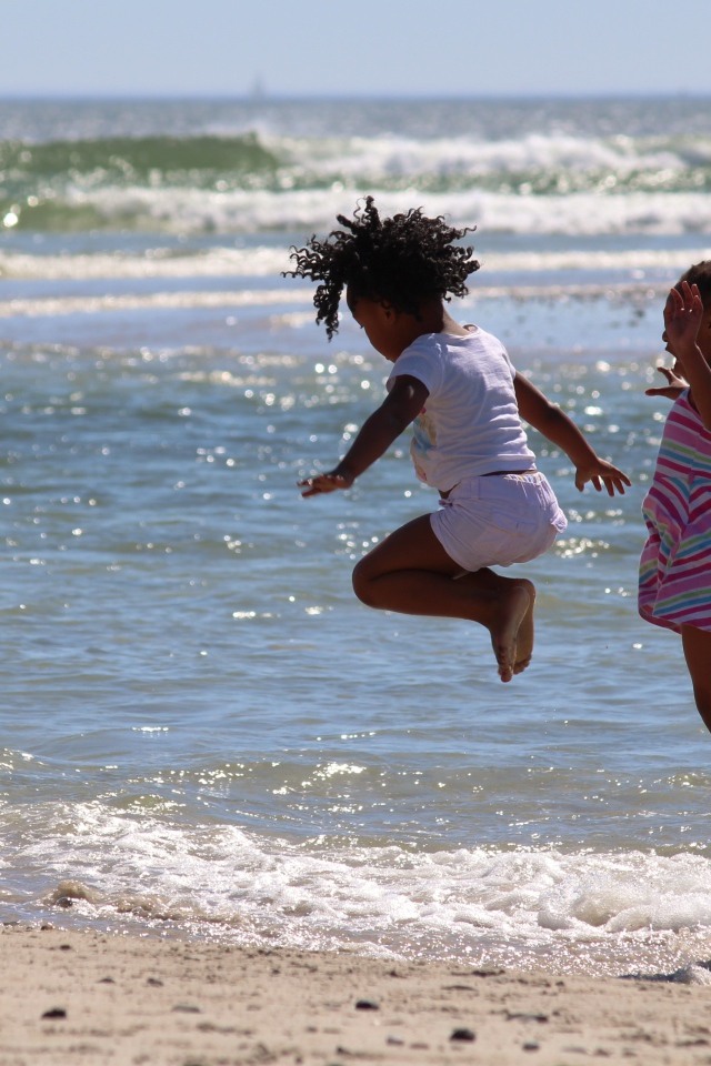 Две маленькие девочки играют на морском берегу