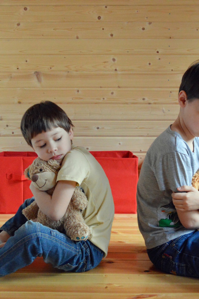 Два маленьких обиженных мальчика сидит на земле