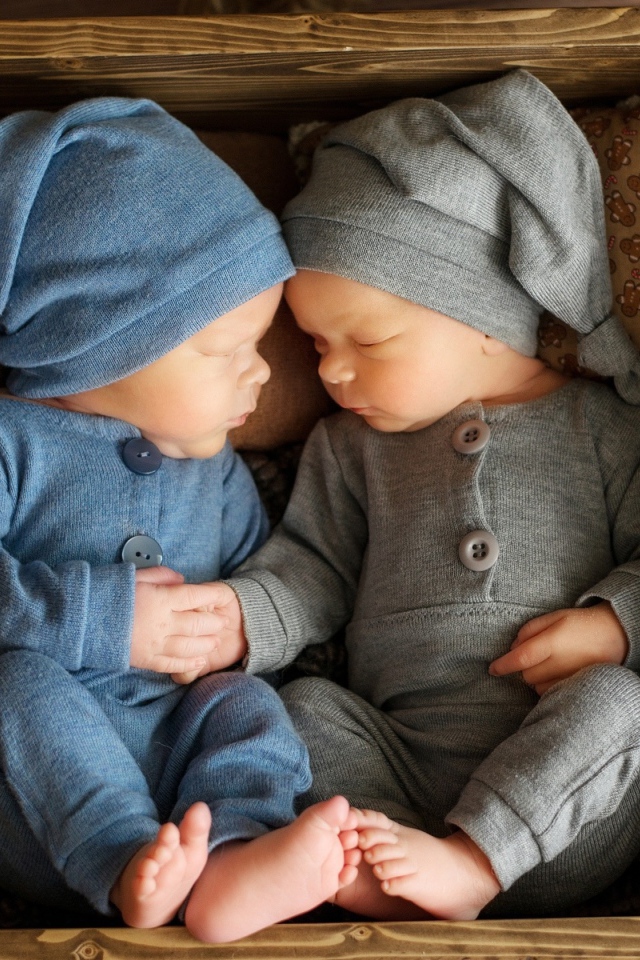 Два маленьких грудных ребенка спят в деревянном ящике