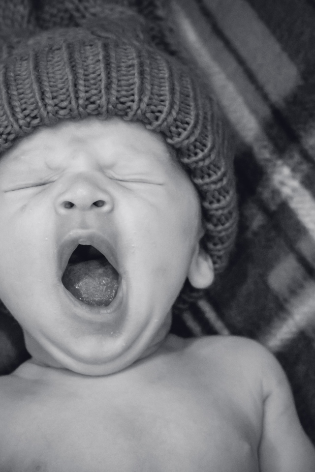 Зевающий ребенок в теплой шапке 