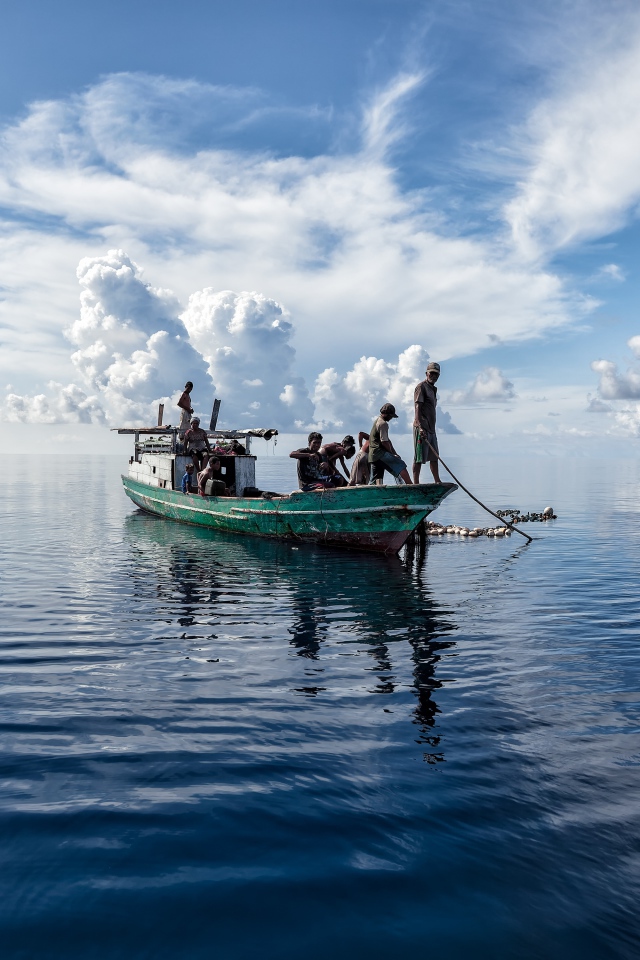 Boat with fishermen at sea with white clouds