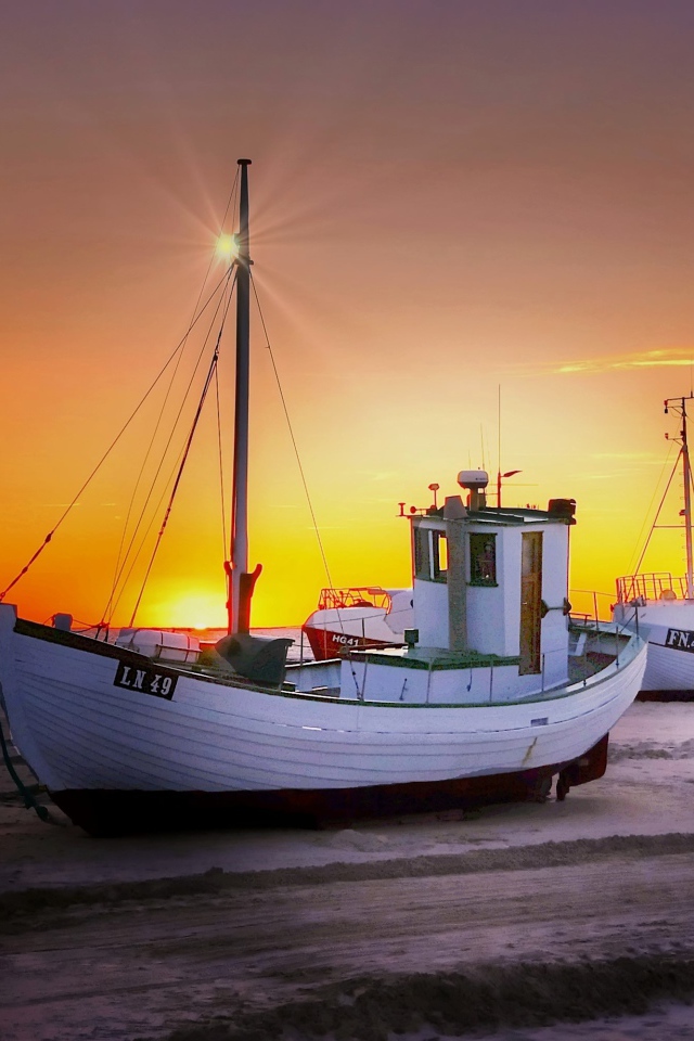 Рыбацкая лодка на берегу на закате 
