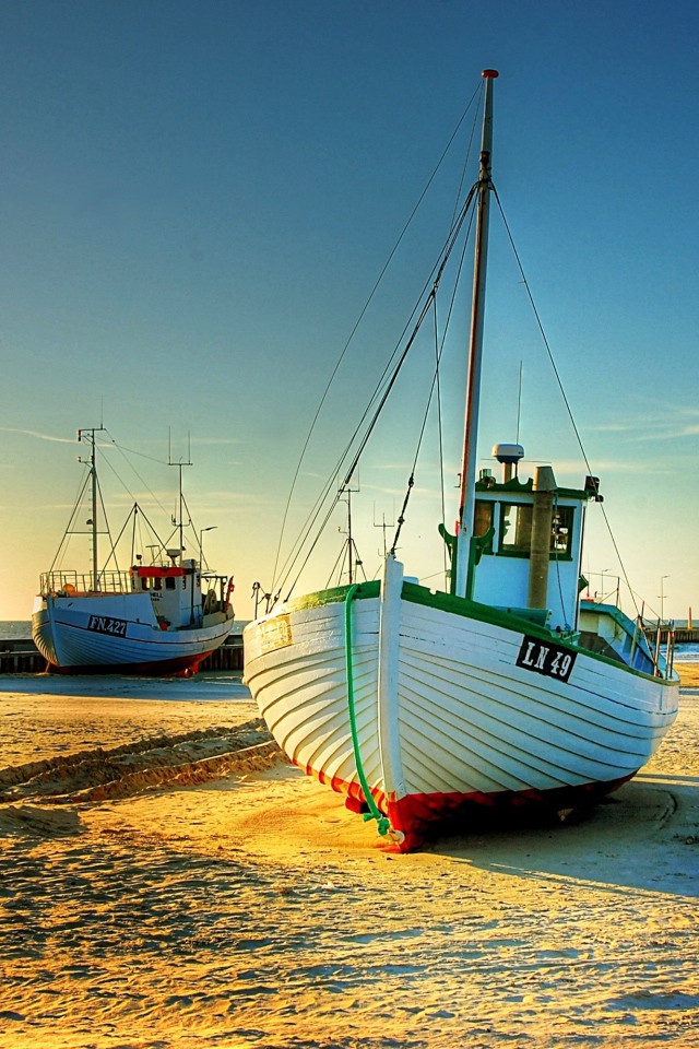Рыболовные лодки в лучах солнца на берегу 