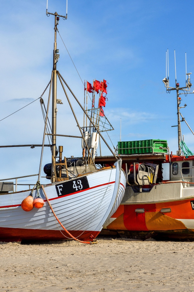 Две рыбацкие лодки стоят на песке у моря 