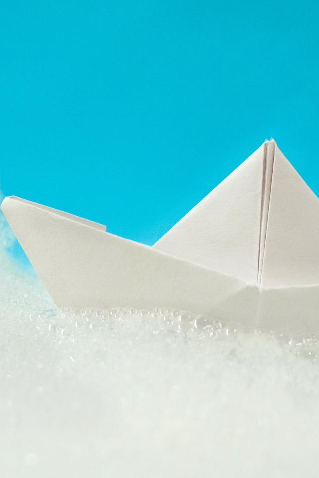 White paper boat on foam on a blue background