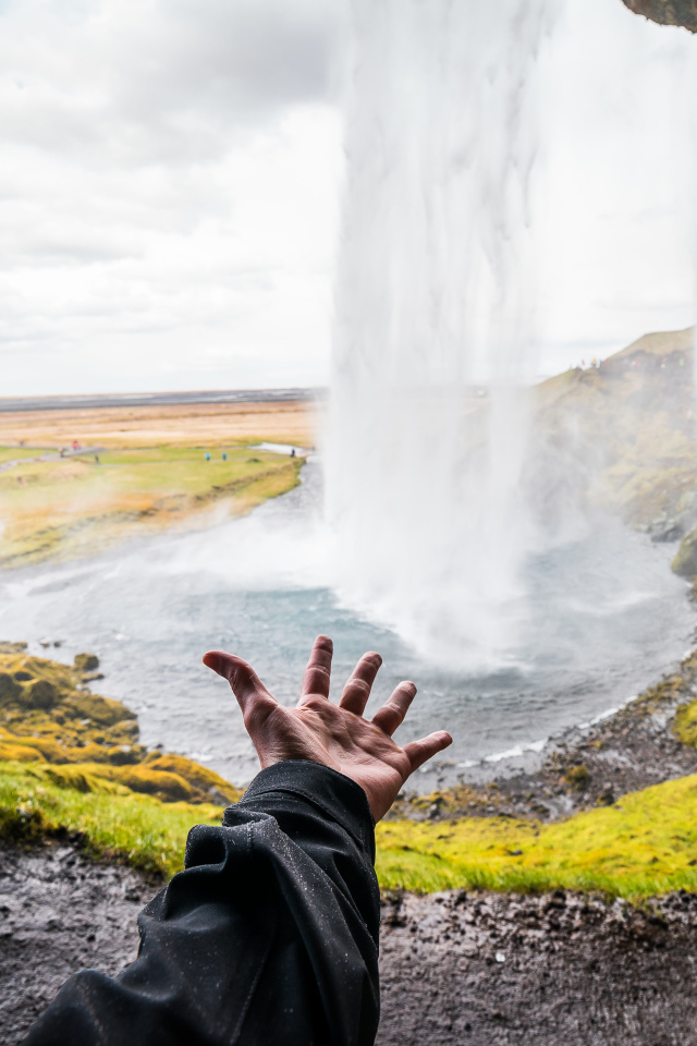 Рука тянется к водопаду Сельяландсфосс, Исландия