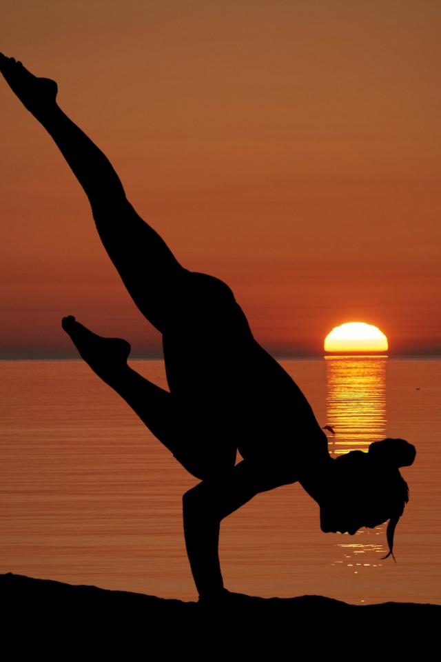 Девушка занимается йогой на закате солнца