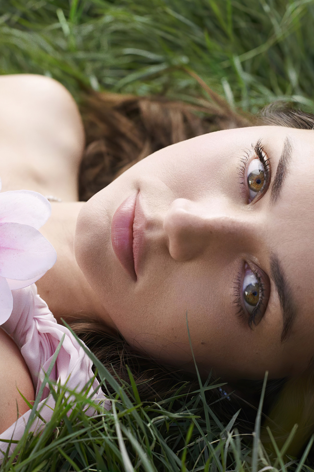 Актриса Ана де Армас лежит на зеленой траве с цветком