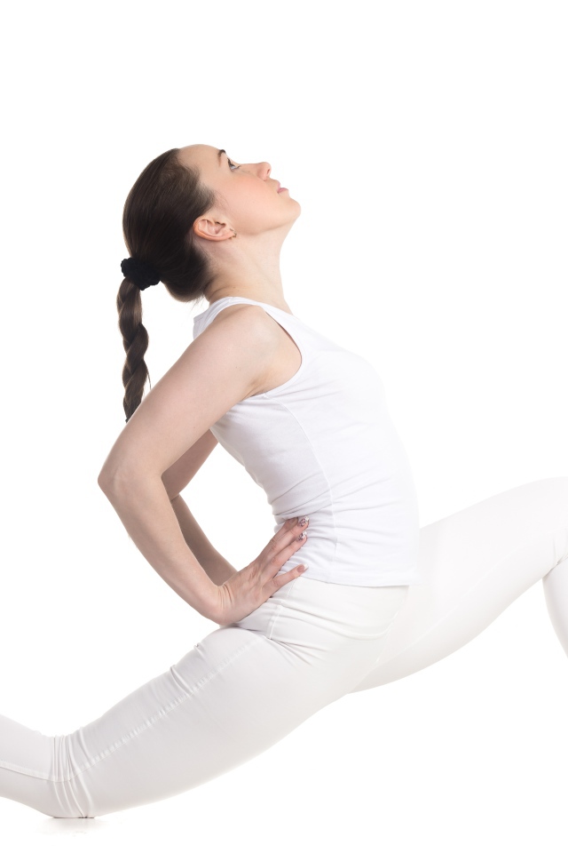 Девушка в белом костюме делает растяжку