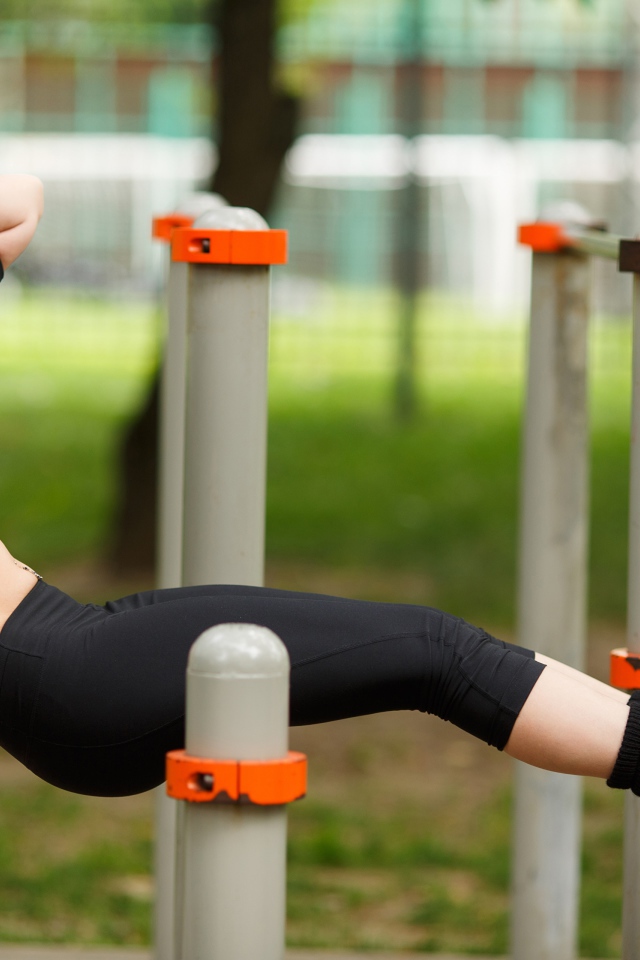 Девушка качает пресс на тренажере на улице