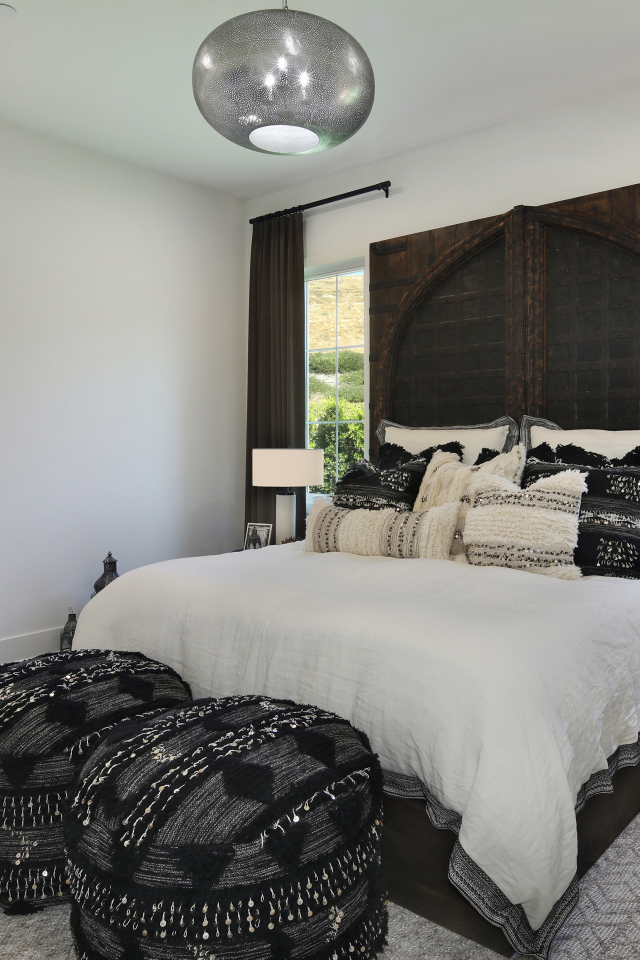 Большая кровать в спальне с большими окнами со шторами