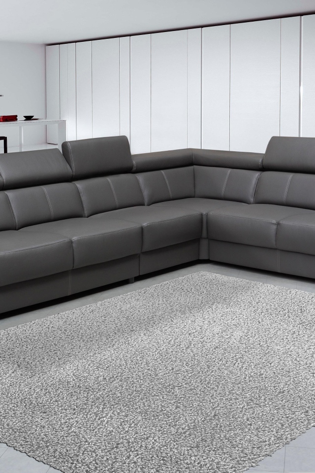 Большой черный угловой диван в комнате с белыми стенами