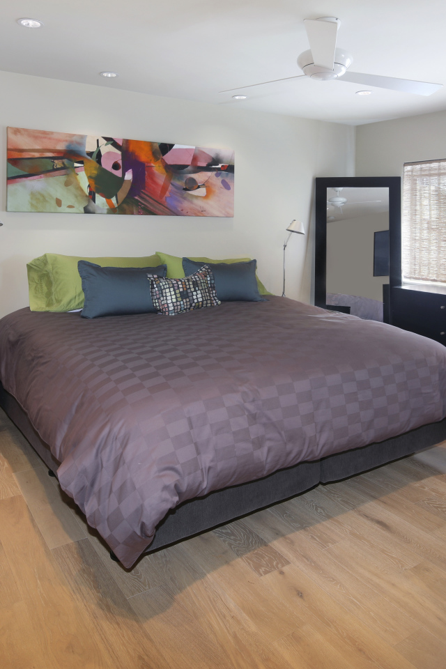 Большая серая кровать в спальне с белыми стенами