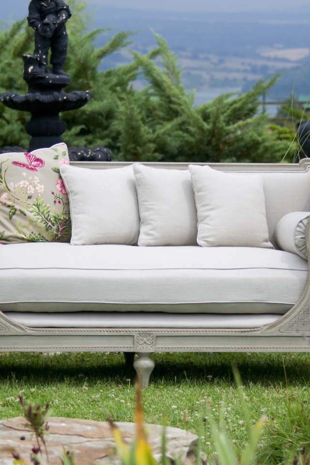 Большой серый диван в саду у пруда 