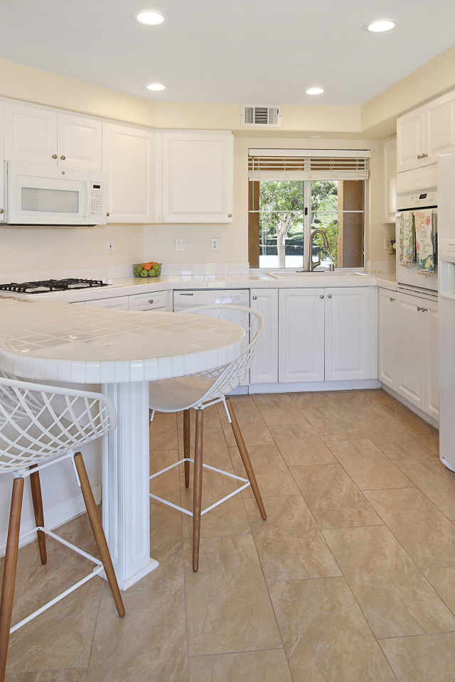 Большой холодильник и белая мебель на кухне 