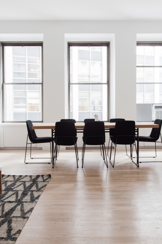 Большой стол с черными стульями в гостиной у окна 