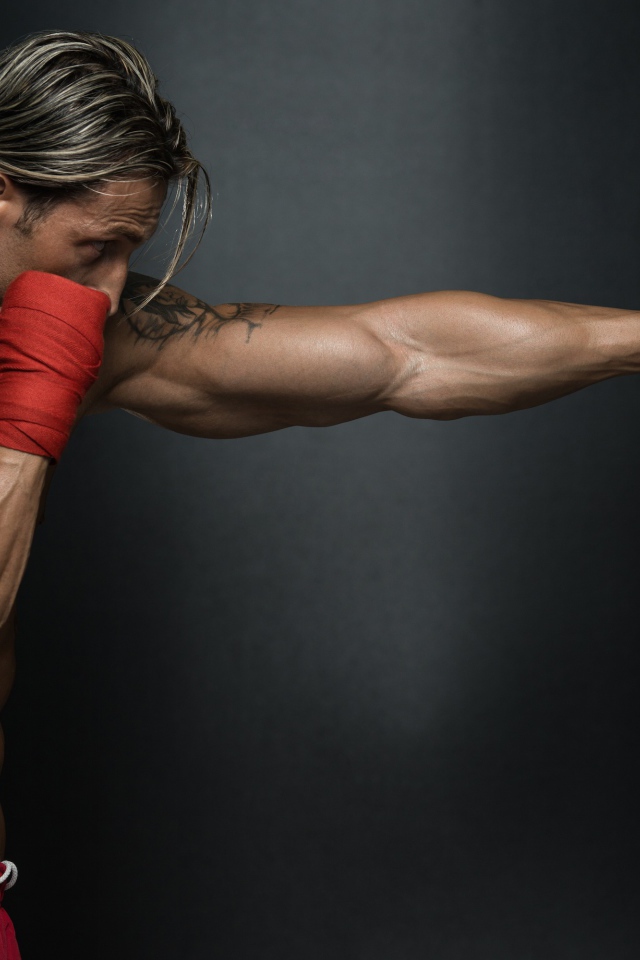 Мужчина боксер с грушей на сером фоне  