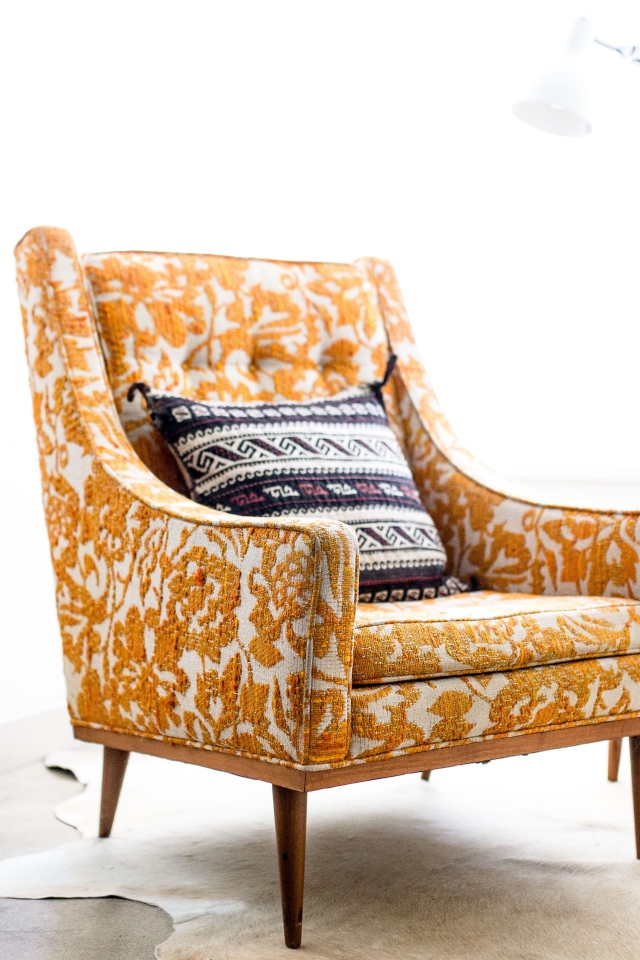 Старое кресло с подушкой в комнате 