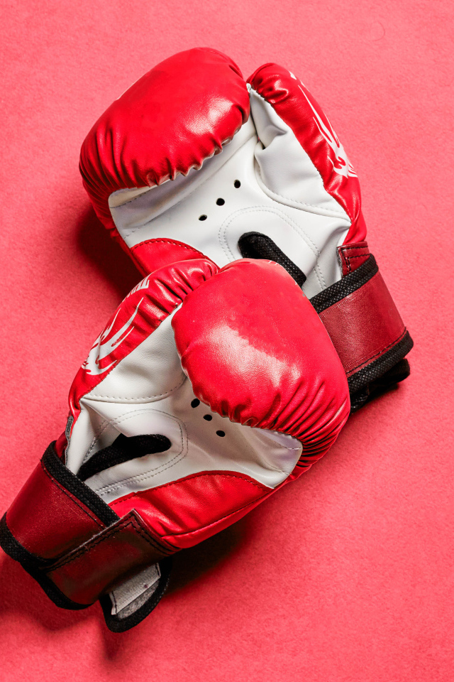 Красные боксерские перчатки на розовом фоне 